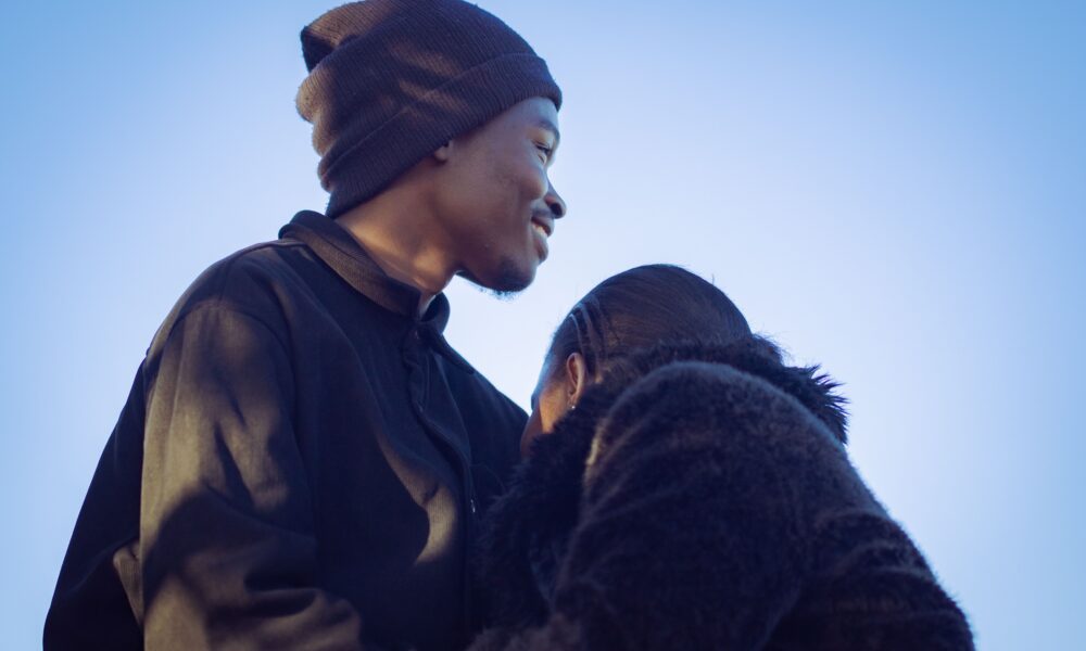 A tender moment between a young couple in Nairobi, reflecting love and warmth under a clear blue sky.